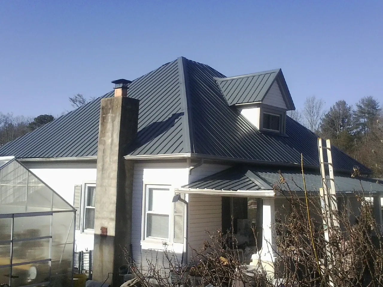 Dark blue standing seam metal roof on a white farmhouse with dormer — Slate & Tile Roof Repair by Roofing Brothers in Garrattsville