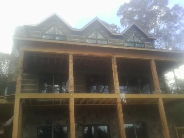 Dormers and porch framing on a large log home under construction — Roof Coating work by our crew in Garrattsville