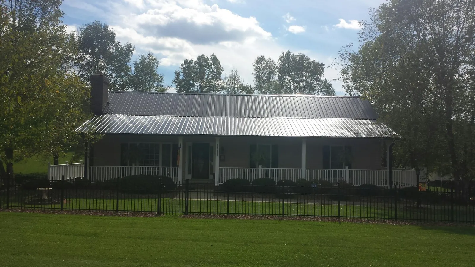 Gray metal roof on a brick ranch with a full width front porch — Gutter Guard Installation work by our crew in Garrattsville
