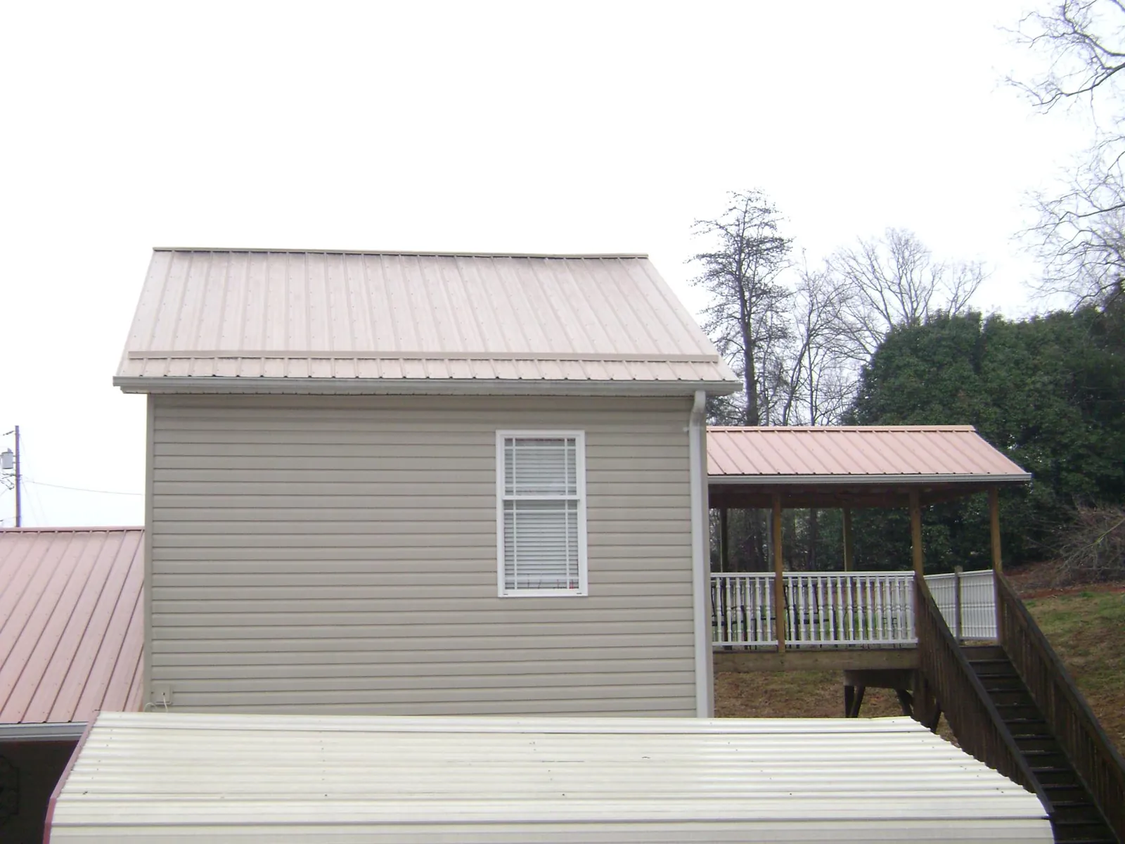 Tan metal roofs on a two story addition and attached porch, from a Roof Replacement job in Garrattsville